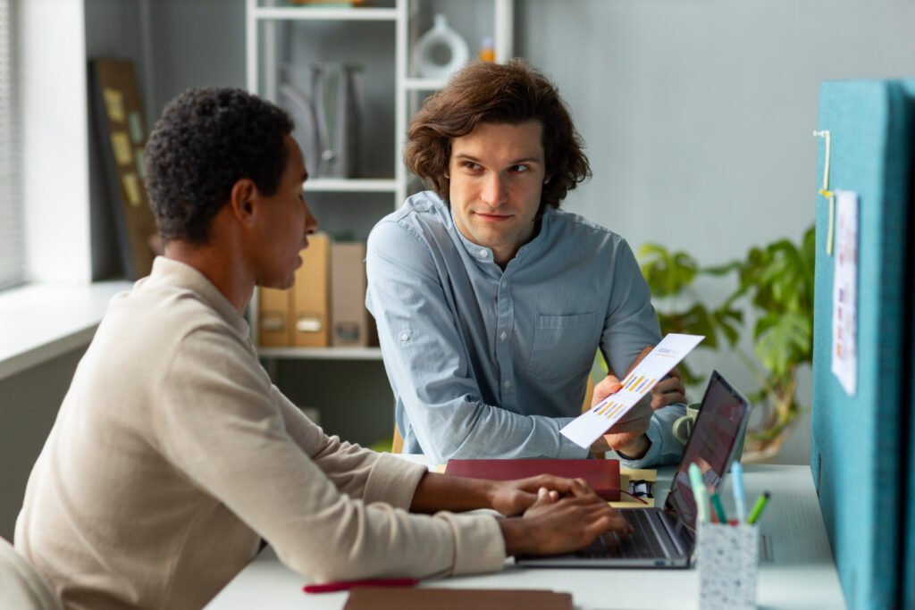 A mentor guiding a young man through job-readiness materials at a desk